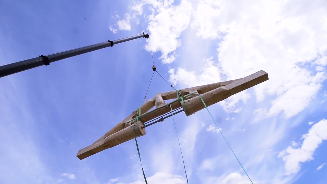 크레인이 큰 나무 지붕 트러스를 들어 올립니다.