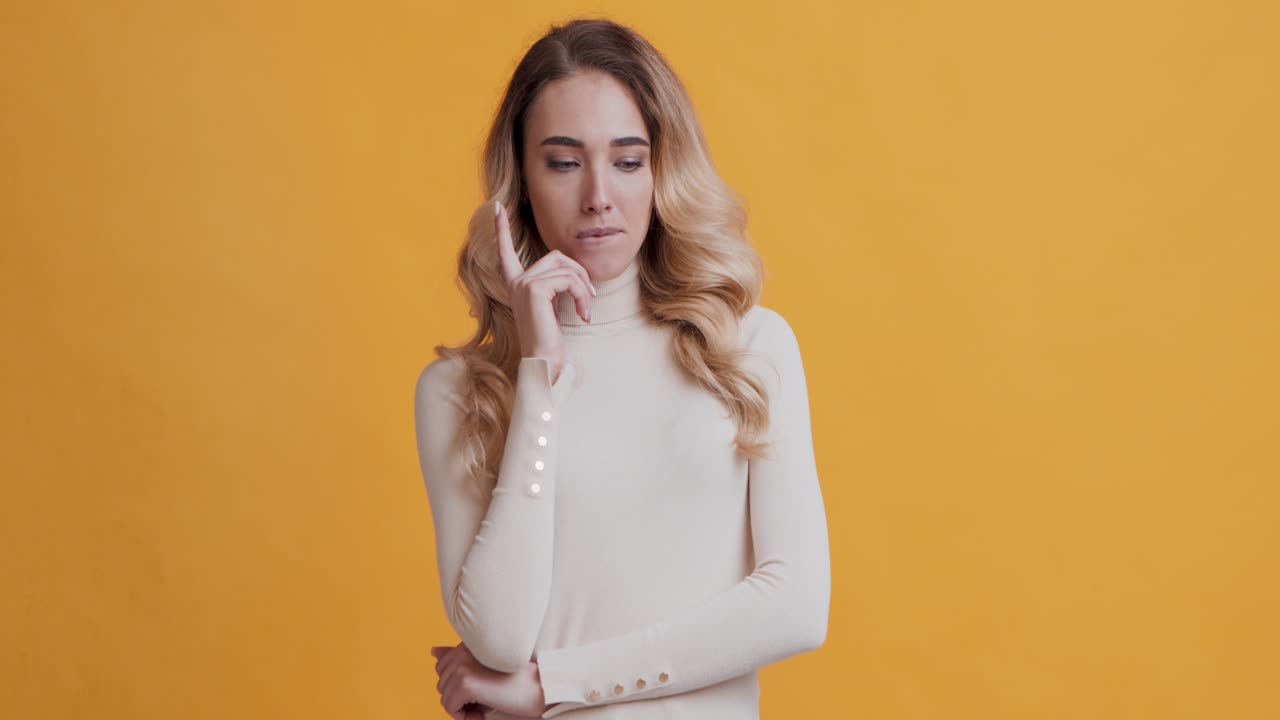 una mujer pensativa con una camiseta beige.