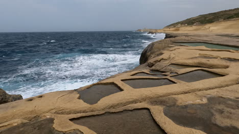 vista aérea de los acantilados de las salinas en el archipiélago maltés más septentrional, el mar mediterráneo ondulado