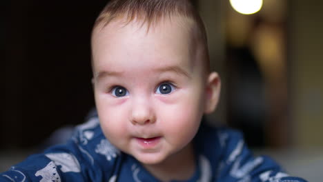 smiling cheerful baby boy looking at camera. close up portrait of a healthy resilient kid wearing blue clothes.