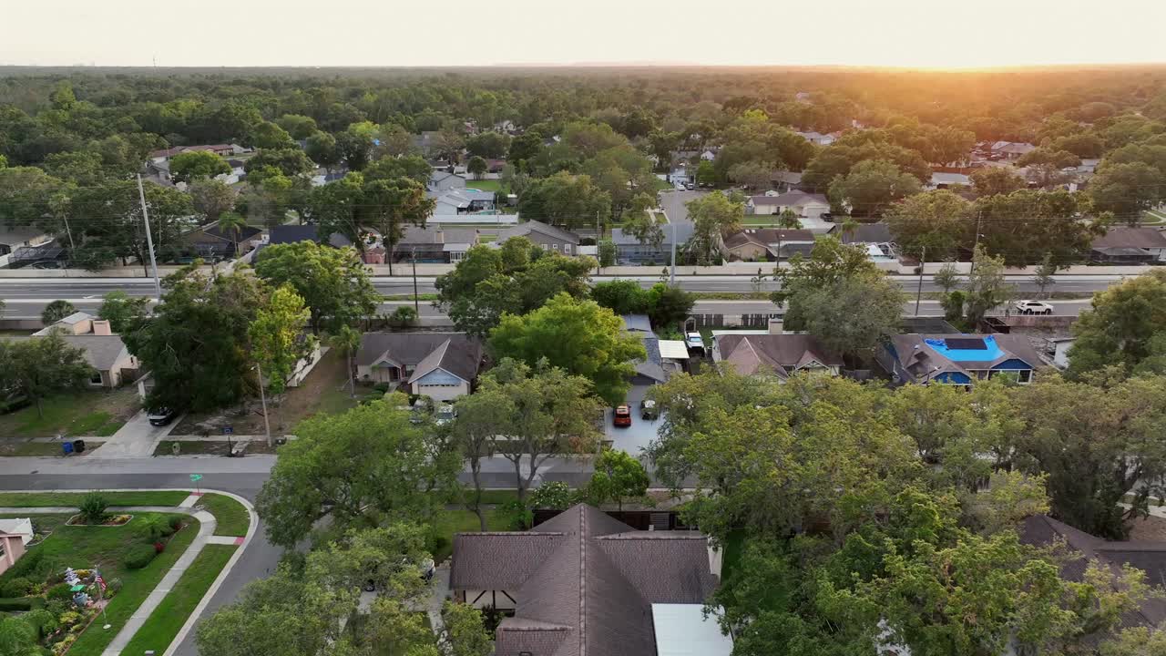 Traffic on main intersection of American town with houses and homes at golden sunset. Aerial lateral wide shot. Single family homes in suburb of bell shoal, FL.