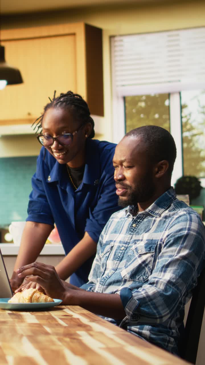 Vertical Video African American freelancer sitting at a kitchen table with a laptop