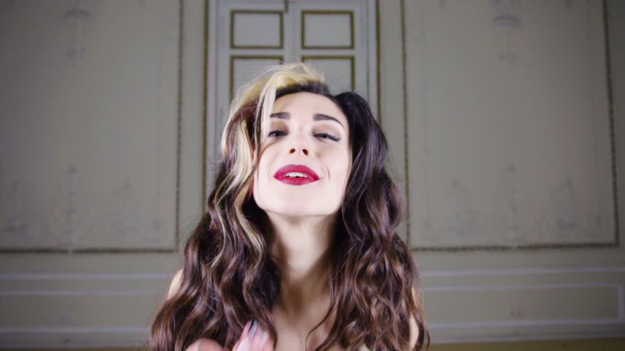 una joven morena con labios rojos sopla confeti dorado