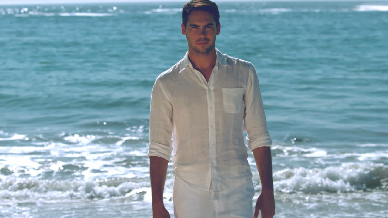 hombre guapo caminando por la playa.