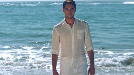 hombre guapo caminando por la playa.