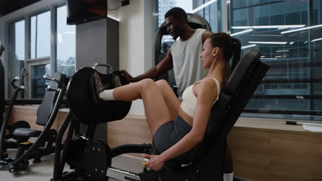 Woman working out on leg press machine with trainer