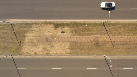 una vista de arriba hacia abajo directamente sobre la mediana de una autopista en un día soleado