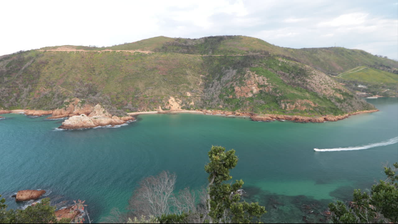 un hermoso día de verano con vistas a las cabezas de knysna desde un mirador con barcos que entran y salen del océano índico