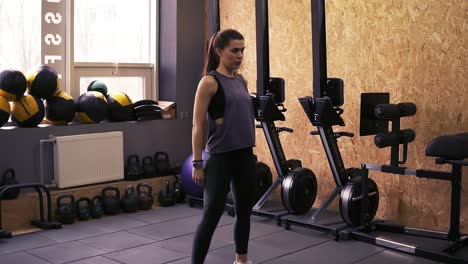 Attractive-slim-brunette-girl-wearing-dryfit-sportswear-doing-squats-in-the-gym-without-any-equipment.-Indoors-footage.-Healthy-lifestyle,-fitness-and-wellbeing.