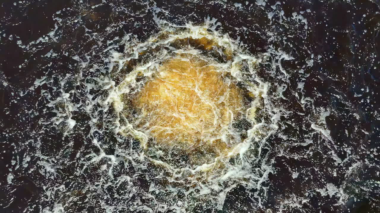 Aerial view of Nord Stream gas leak disturbance in dark Baltic Sea water under a clear sky, showing a violent brown and white surface eruption