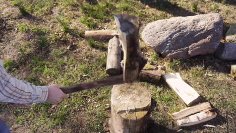 vista superior de un hombre irreconocible cortando leña con un hacha fuera de una casa de campo