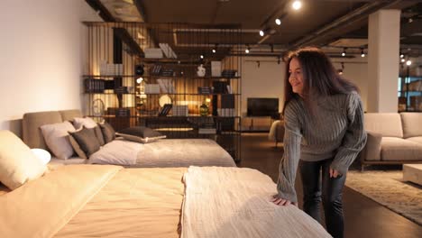 concentrated thoughtful beautiful woman chooses soft beds touching them in furniture salon concentrated thoughtful beautiful woman chooses soft beds touching them in furniture salon a selection of comfortable furniture for living and for the bedroom