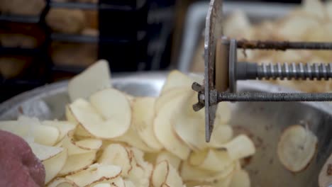 Closeup-of-potato-going-into-a-machine-and-then-spinning-ribbons-of-curly-potatoes-coming-out-of-a-tornado-cutter