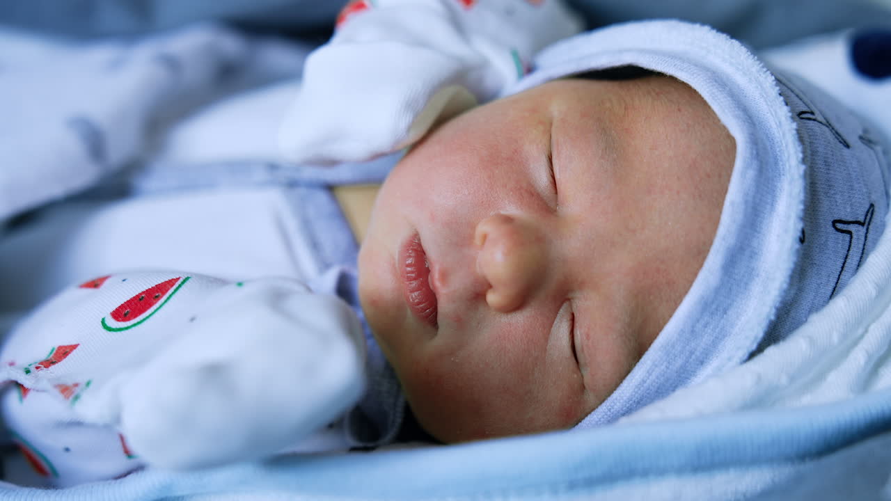 Lovely sleeping baby few days old. Angelic infant in cap and shirt resting. Close up.