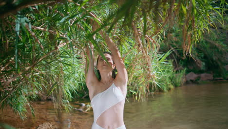 dreamy woman walking bamboo jungles. gentle model touching tropical brunches