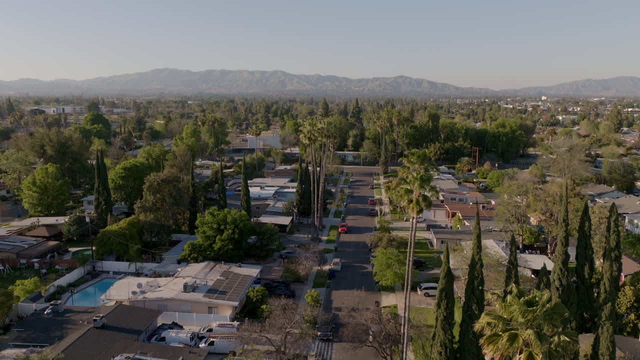 On a warm summer day, looking down at downtown Los Angeles from an elevated position offers a serene view of the city's private residences, set against a picturesque mountainous backdrop