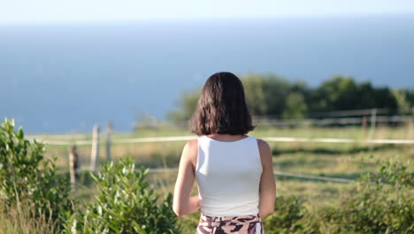 Spanish-Woman-Pointing-at-Ocean,-Sunny-Beach-Day