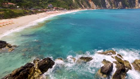 Petani-beach-in-kefalonia-with-turquoise-waters-and-beachgoers,-sunny-day,-aerial-view