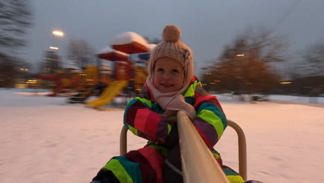 little child having exciting ride on playground spinner winter view