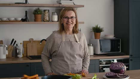 retrato de una mujer mayor caucásica de pie en la cocina y sonriendo