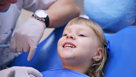 happy girl in dentist chair. portrait of a little smiling child showing her small teeth to the camera. child dentist's visit.