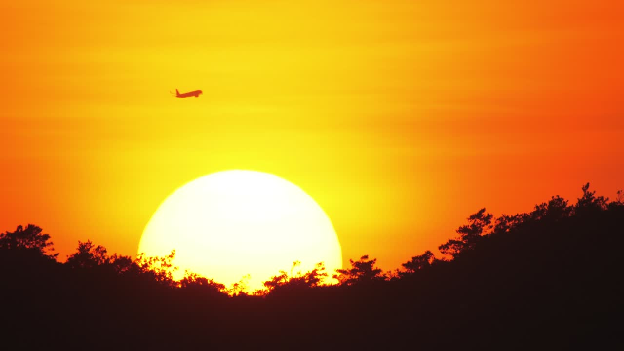 해가 지는 배경에서 지나가는 여객기,