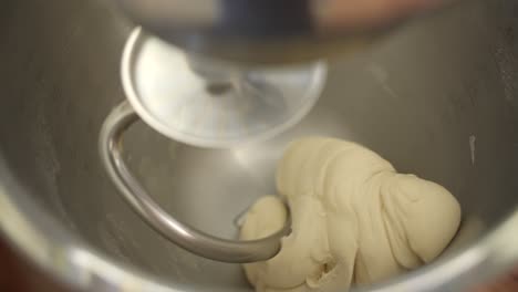 bread dough preparation with electric mixer in stainless steel bowl, close up