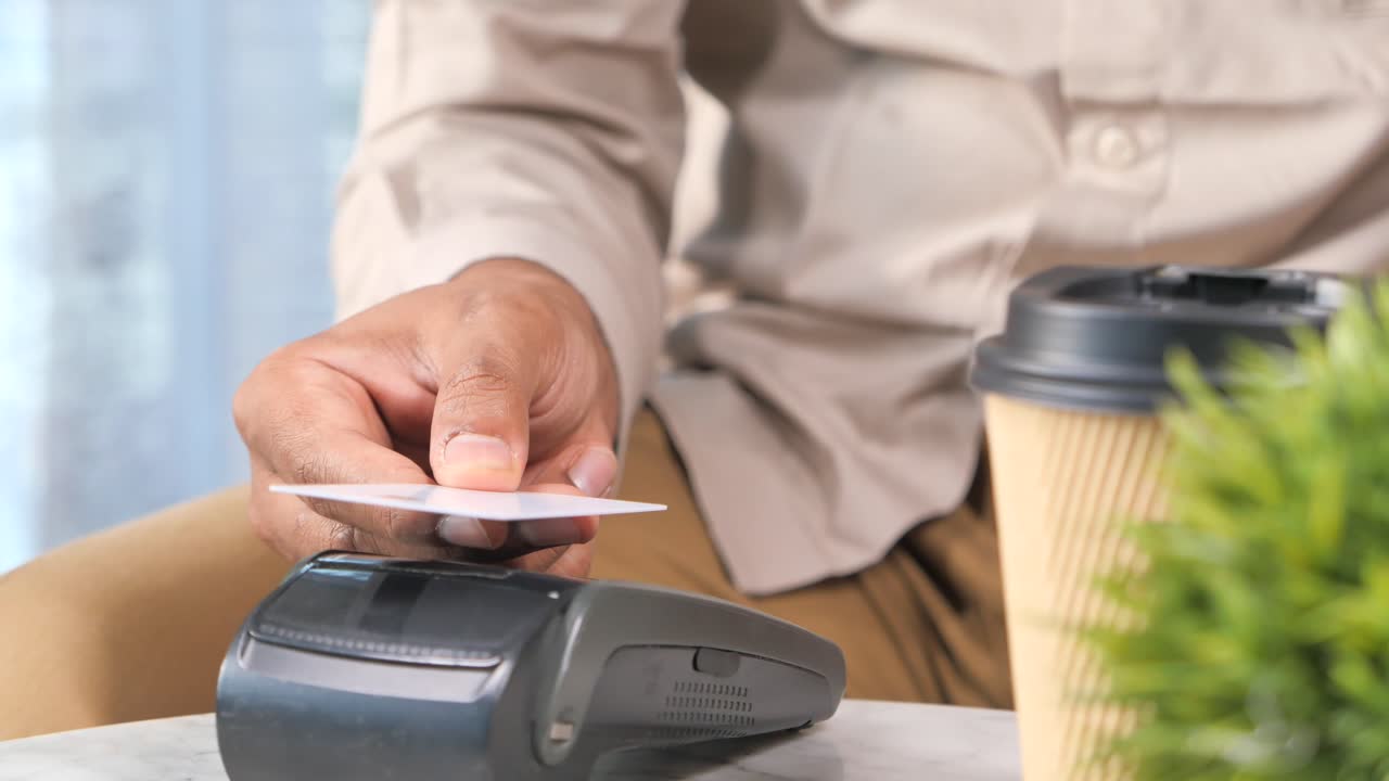 カフェでクレジットカードで非接触決済をする男性