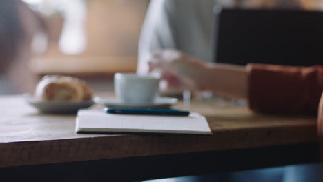 Cerrar-Las-Manos-De-Una-Mujer-De-Negocios-Usando-Un-Teléfono-Inteligente-En-Una-Cafetería-Bebiendo-Café-Enviando-Mensajes-De-Texto-Leyendo-Mensajes-De-Correo-Electrónico-Escribiendo-Notas-Intercambiando-Ideas-Disfrutando-De-Un-Restaurante-Ocupado