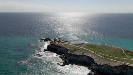 Aerial-of-Tourists-walking-on-a-cliff-at-Isla-Mujeres,-Mexico