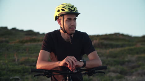 motociclista masculino con casco disfruta del descanso después de un largo viaje al atardecer, de mano