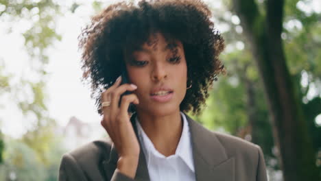 woman answering phone call walking city park closeup. lady talking on smartphone