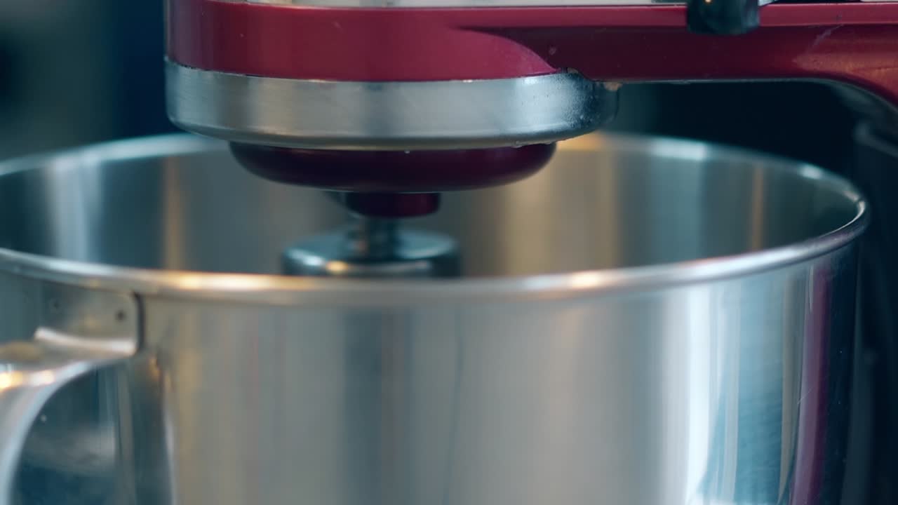 el mezclador rojo mezcla los ingredientes en un cuenco de metal con batidor