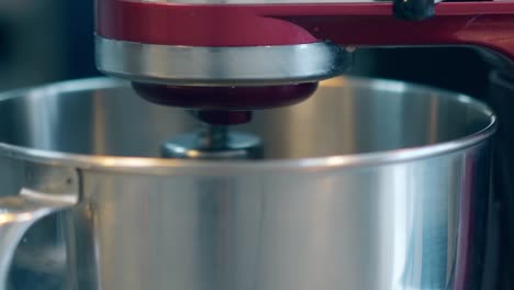 red mixer blends ingredients in metal bowl with whisk