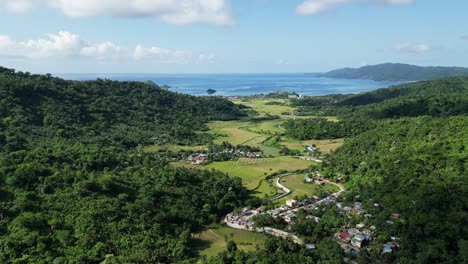 aerial view of town surrounded by green mountains overlooking the blue sea in baras, catanduanes, philippines