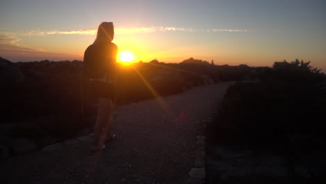 ralenti d'une jeune femme blonde marchant au sommet de la montagne de la table pendant le coucher du soleil bloquant la lumière