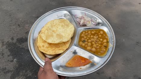 chole bhature old delhi street food held in hand at a roadside shop in india