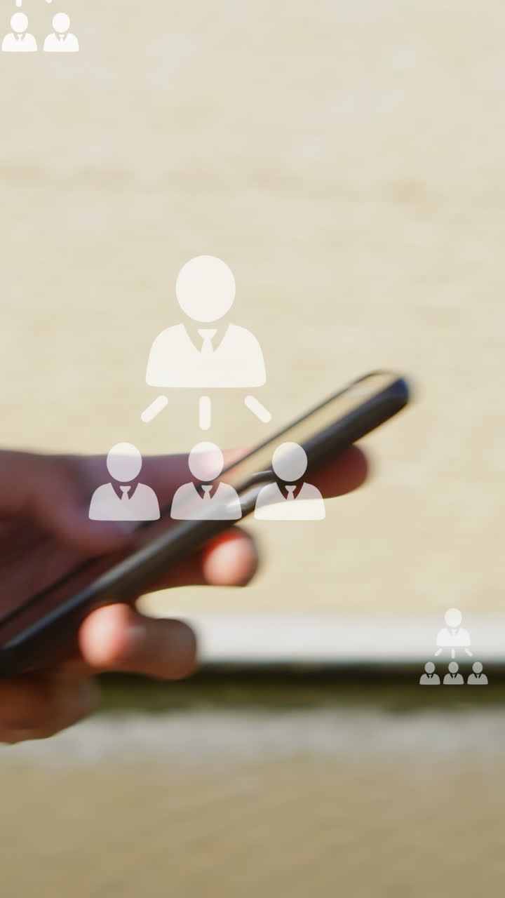 animación de iconos de usuario sobre las manos de un hombre biracial que usa un teléfono inteligente en la ciudad