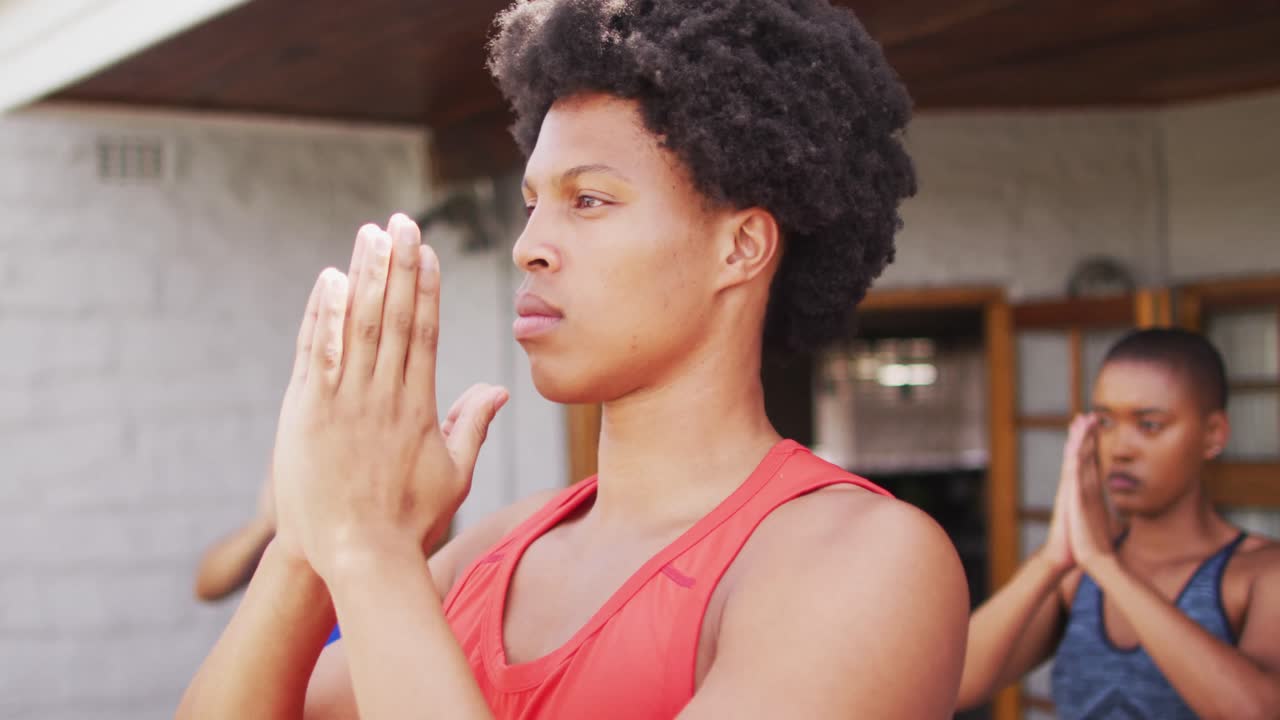 Uomo afroamericano che pratica yoga con un gruppo di amici di diverse etnie in giardino.