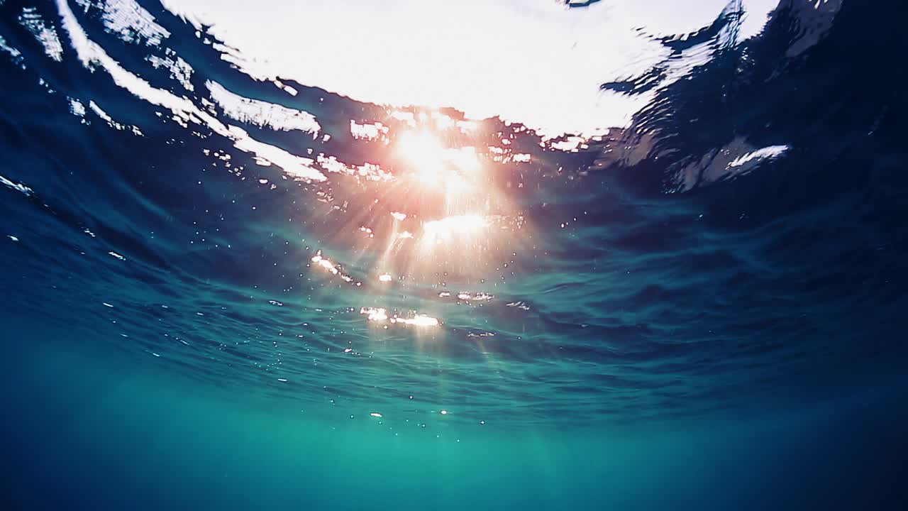 ola bajo el agua, bucle. superficie del mar vista bajo el agua. clip de bucle sin problemas de la superficie del agua con llamarada solar