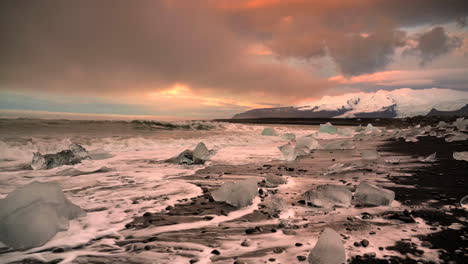 plano general de la playa de diamantes durante el amanecer místico en islandia - olas que llegan a la orilla con icebergs en cámara lenta