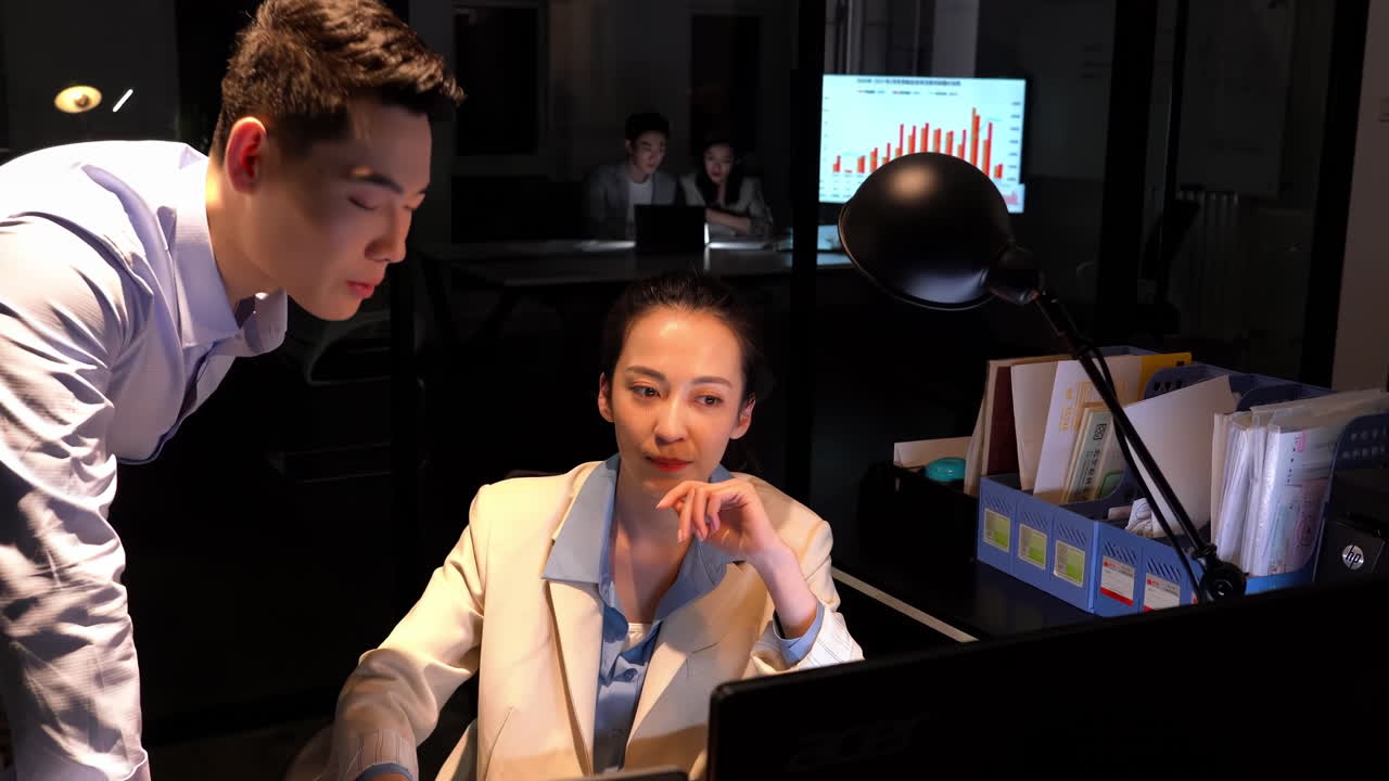 Business people working late at night in office discussing, planning schedule work together. Group of casual business marketing team analyzes data, discusses sales using charts on a computer screen.