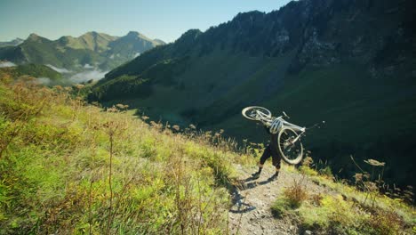 A-mountain-biker-is-carrying-his-bike-up-an-alpine-trail-in-autumn