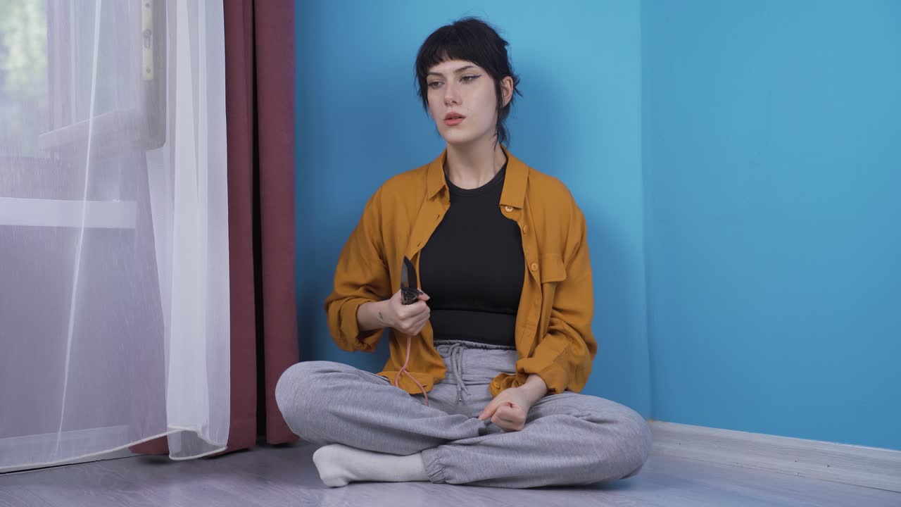 una joven agresiva y psicópata jugando con un cuchillo.