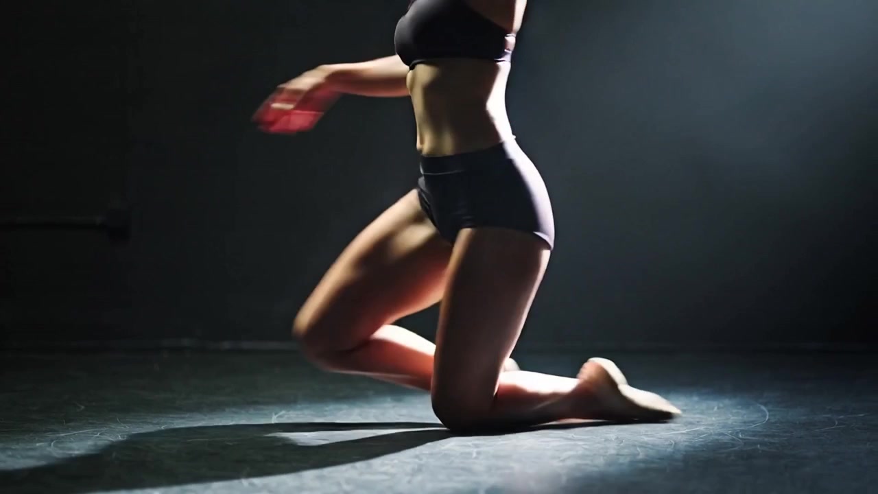 Riflettore puntato, ballerina che si esibisce, gira sul pavimento, ruota, incrocia la gamba in abbigliamento da danza nero