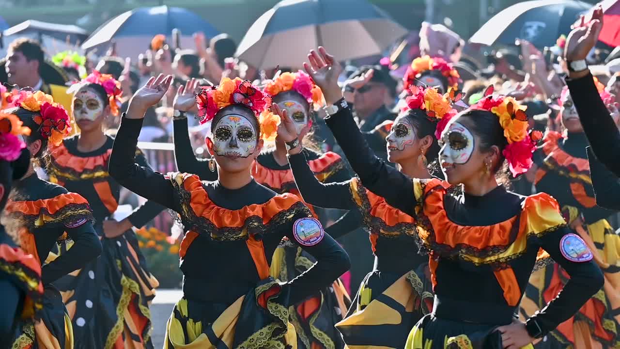 Dancers in colorful and vibrant costumes celebrate in the Day of the Dead parade highlighting Mexican culture