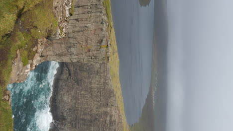 vertical - rock formation surrounding lake sorvagsvatn in fog. vagar island, faroe islands.