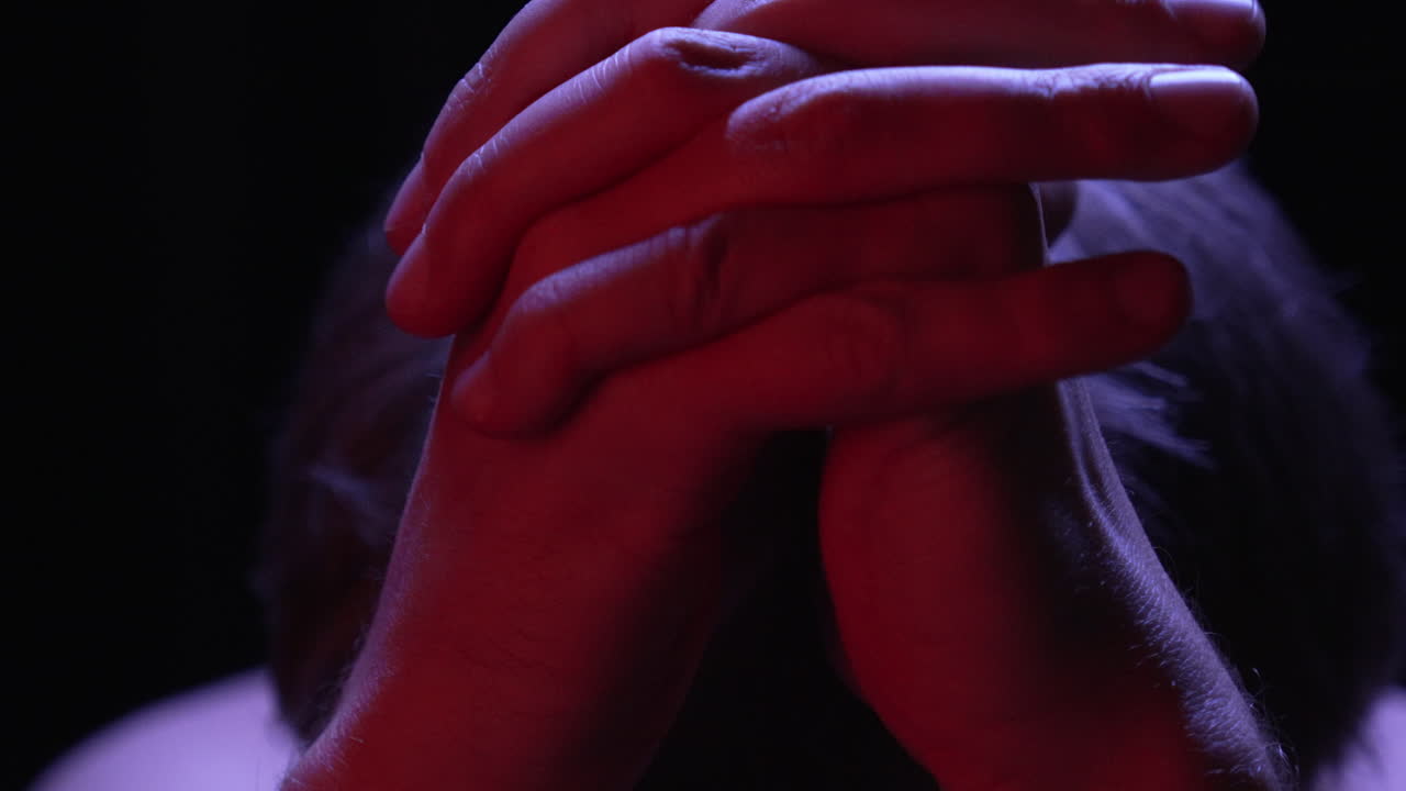 individuo estresante se une en oración a dios, iluminado por luz roja superior