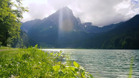 alpensee eingebettet in den berg mit menschen, die in der nähe des weges spazieren gehen