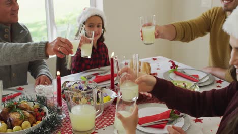 Glückliche-Kaukasische-Mehrgenerationenfamilie-Mit-Weihnachtsmützen-Beim-Weihnachtsessen
